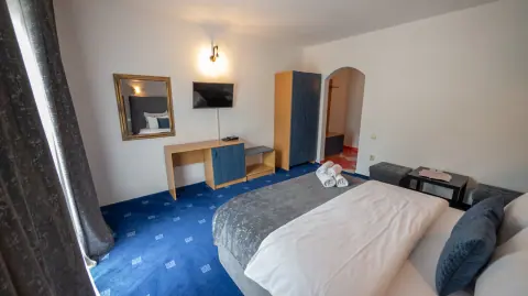 Blue room with a bed, television, desk and wardrobe