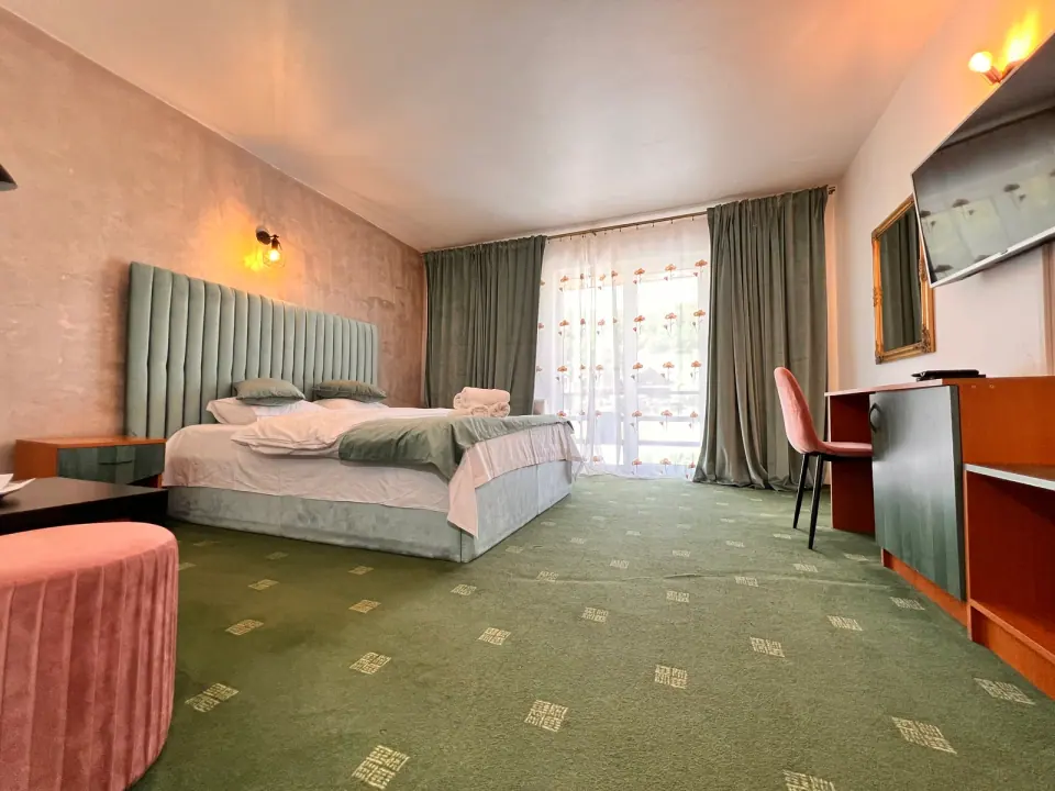 Double bedroom with green carpet, armchair and balcony