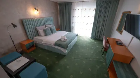 Green room with a double bed, television and balcony