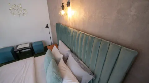 Green headboard and wall lights in the guesthouse room