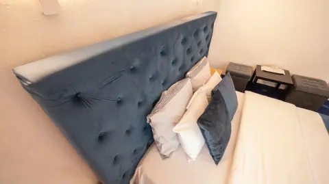 Blue headboard, cushions and white bed linen