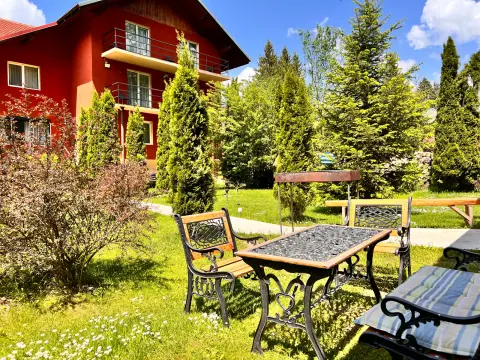 Table and chairs in the garden with the guesthouse and fir trees behind