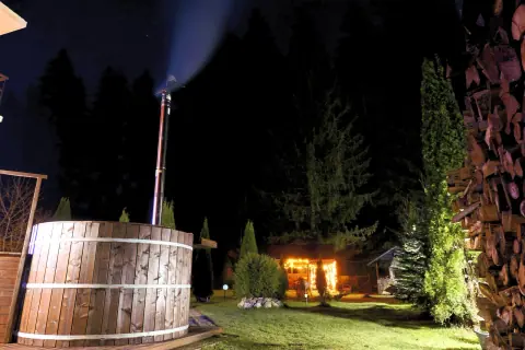 Wooden hot tub lit in the guesthouse garden at night