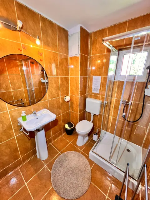 Bathroom with orange tiles, a round mirror and shower