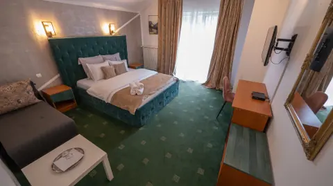 Room with a green double bed, sofa and balcony