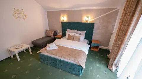 Green double bed, small table and sofa in the room