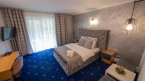 Double bed with a grey headboard, blue carpet and balcony