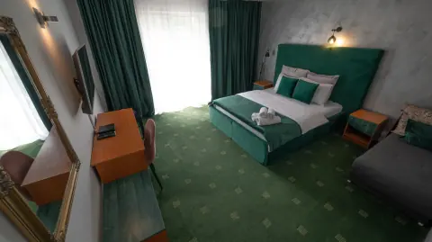 Green room with a double bed, armchair and balcony