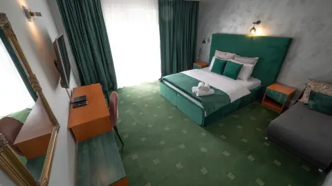 Green double bed, green carpet and open curtains