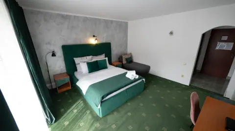 Room with a green double bed and wardrobe near the entrance
